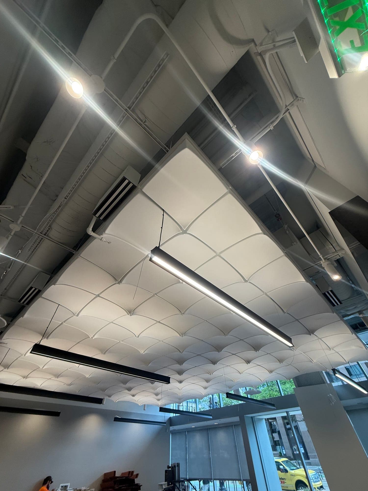 Sculptural acoustic cloud ceiling with pendant lighting, installed by SGS in a commercial atrium